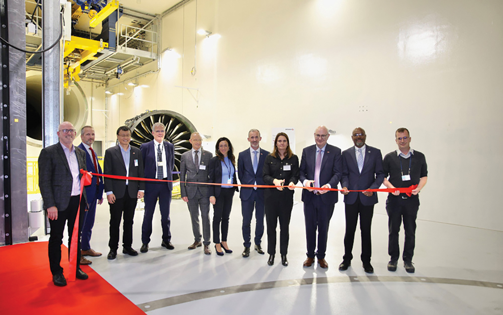 Eleven people holding red ribbon, ready for cutting