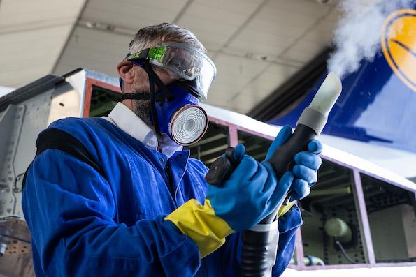 maintenance technician wearing protective gear and holding a cleaning device