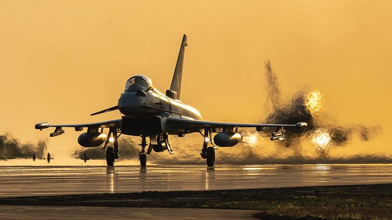 Eurofighter aircraft on runway against yellow sky