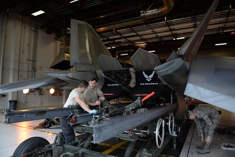 Air Force personnel work on an F119 engine